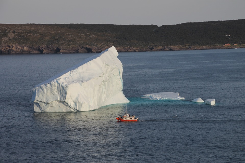 Newfoundland — Iceberg with small red boat